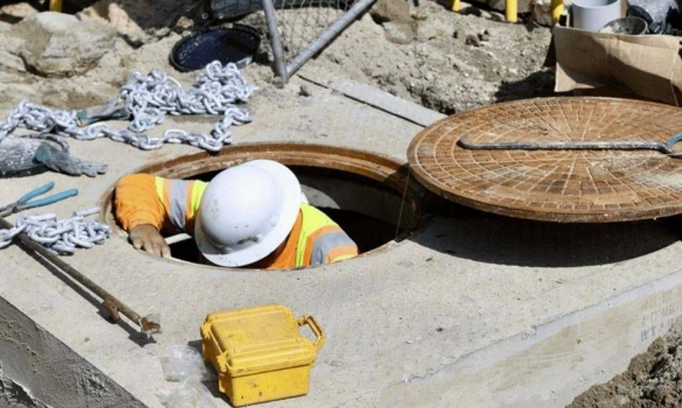 Worker entering a sewer manhole, illustrating a typical confined space.